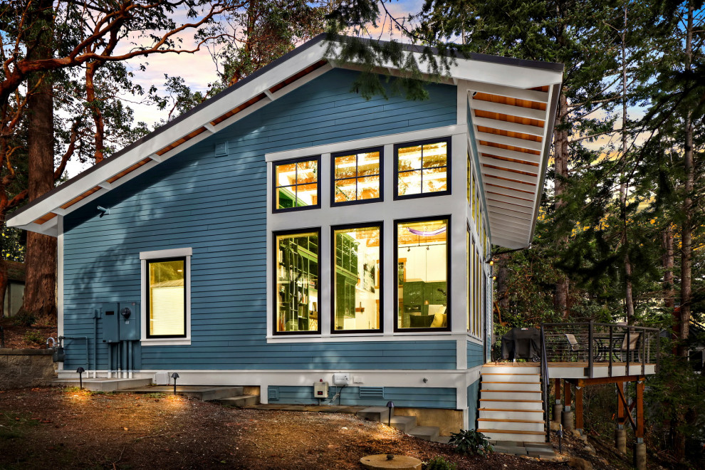 Стильный дизайн: маленький, одноэтажный, деревянный, синий мини дом в морском стиле с полувальмовой крышей, металлической крышей, коричневой крышей и отделкой планкеном для на участке и в саду - последний тренд