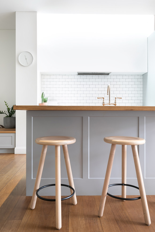 Inspiration for a mid-sized modern galley eat-in kitchen in Sydney with flat-panel cabinets, white cabinets, wood benchtops, white splashback, with island and white benchtop.