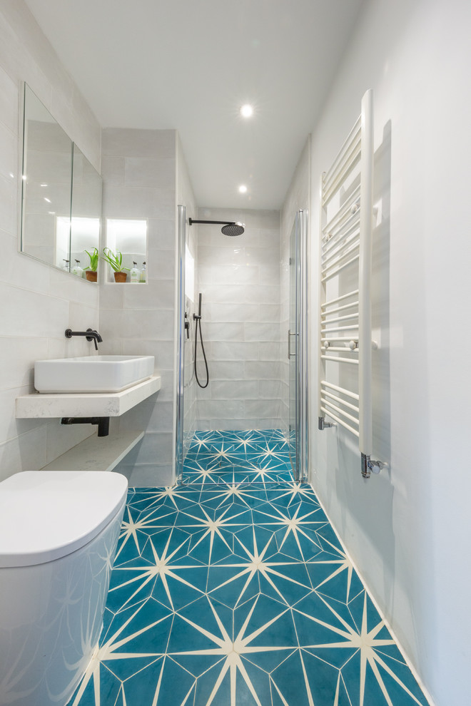 Mediterranean 3/4 bathroom in London with an alcove shower, white tile, white walls, cement tiles, a vessel sink, blue floor, a hinged shower door and white benchtops.