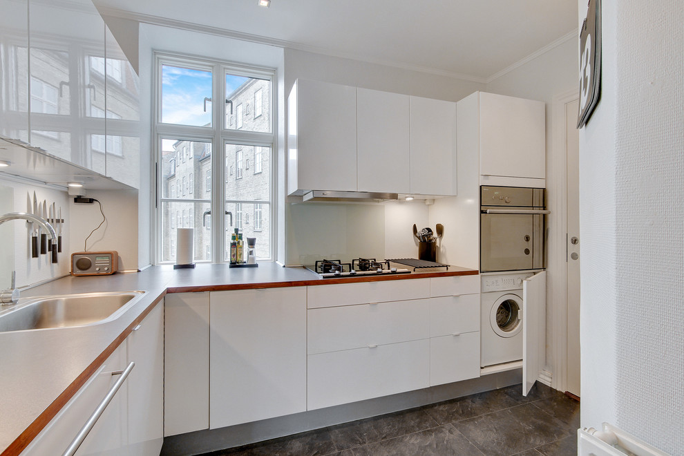 Inspiration for a mid-sized scandinavian l-shaped separate kitchen in Aalborg with a drop-in sink, flat-panel cabinets, white cabinets, stainless steel appliances, no island, laminate benchtops, grey splashback, glass sheet splashback and ceramic floors.