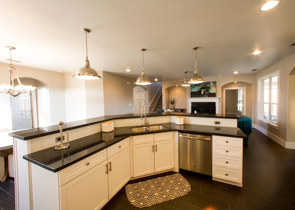 Example of a transitional porcelain tile home design design in Austin with an undermount sink, shaker cabinets, white cabinets, granite countertops, white backsplash, glass sheet backsplash, stainless steel appliances and an island