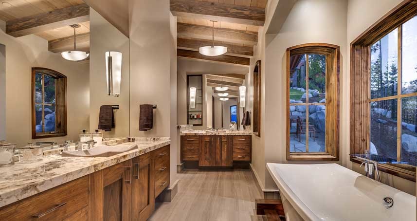 This is an example of a large country master bathroom in Sacramento with shaker cabinets, medium wood cabinets, a freestanding tub, a corner shower, a two-piece toilet, beige tile, brown tile, marble, beige walls, laminate floors, a drop-in sink, marble benchtops, beige floor and a hinged shower door.