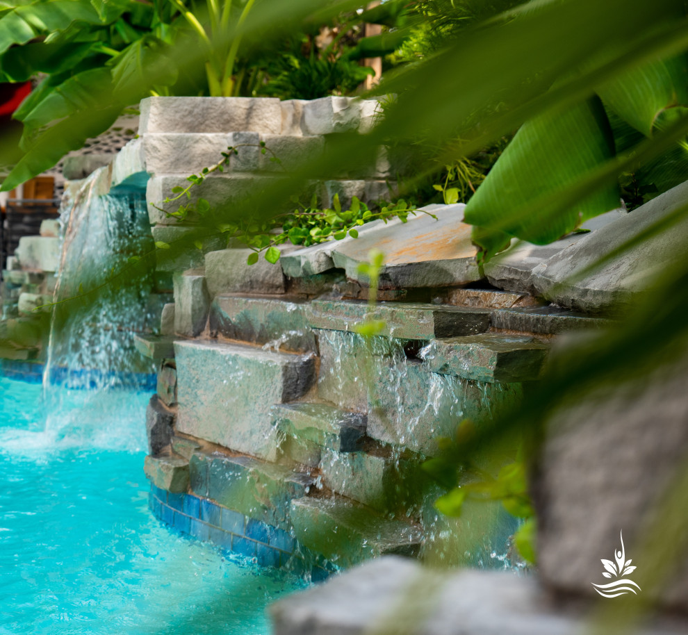 Diseño de piscina natural asiática extra grande a medida en patio trasero con privacidad y adoquines de piedra natural