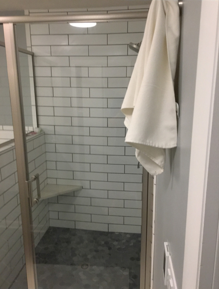 Aménagement d'une grande salle de bain principale moderne avec des portes de placard blanches, une baignoire posée, une douche d'angle, WC à poser, un carrelage blanc, un carrelage métro, un mur gris, un sol en carrelage de céramique, un plan de toilette en surface solide, un sol noir, un plan de toilette blanc, un banc de douche, meuble simple vasque et meuble-lavabo encastré.