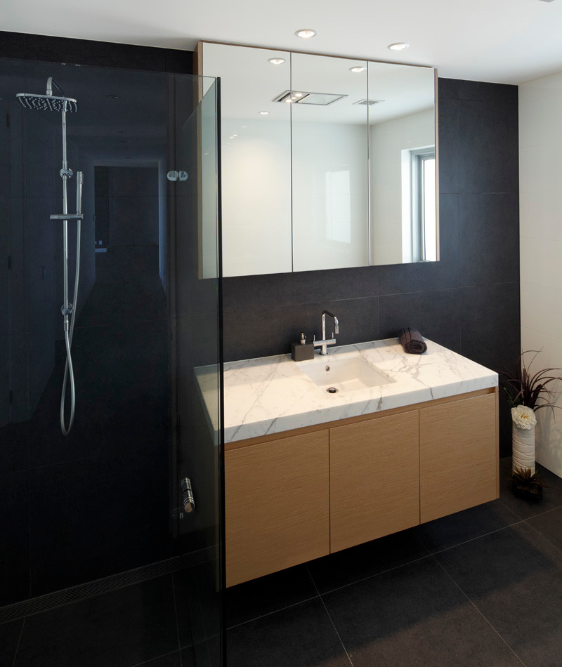 Small contemporary 3/4 bathroom in Sydney with an undermount sink, flat-panel cabinets, light wood cabinets, marble benchtops, a corner shower, black tile, ceramic tile, black walls and porcelain floors.