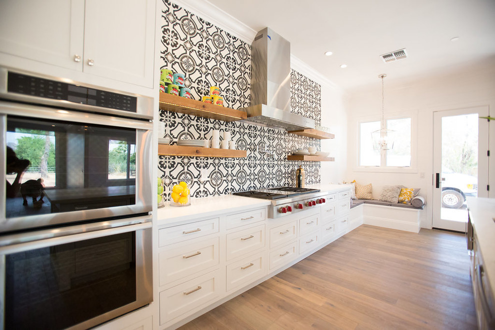 Photo of a large transitional galley eat-in kitchen in Phoenix with a double-bowl sink, white cabinets, stainless steel appliances, with island, recessed-panel cabinets, multi-coloured splashback, medium hardwood floors, quartz benchtops, cement tile splashback and grey floor.