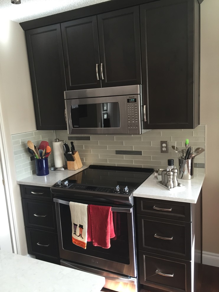 Example of a mid-sized transitional single-wall dark wood floor open concept kitchen design in Calgary with a double-bowl sink, shaker cabinets, dark wood cabinets, white backsplash, subway tile backsplash, stainless steel appliances and an island