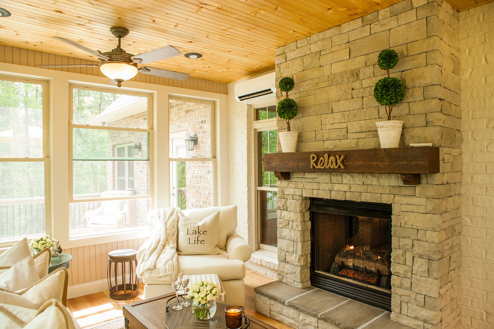 Design ideas for a country sunroom in Charlotte with light hardwood floors, a stone fireplace surround, a standard ceiling and a standard fireplace.
