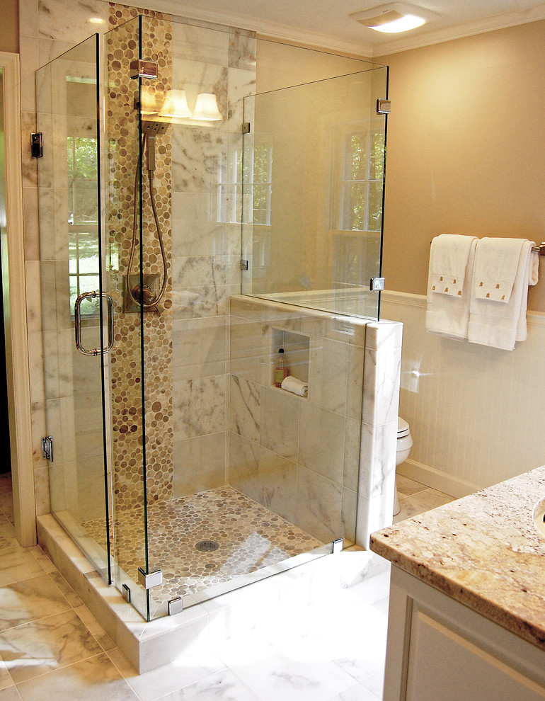 Photo of a mid-sized transitional master bathroom in Raleigh with an undermount sink, raised-panel cabinets, white cabinets, granite benchtops, an alcove shower, a two-piece toilet, white tile, pebble tile, grey walls and marble floors.
