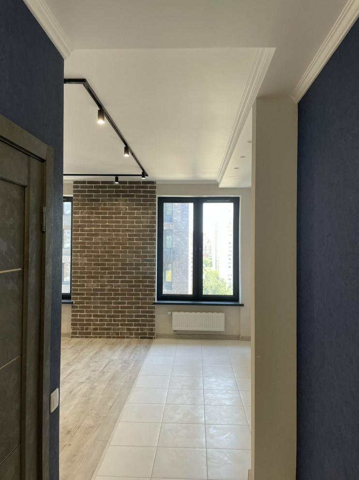 Foto de recibidores y pasillos actuales de tamaño medio con paredes azules, suelo de baldosas de cerámica, suelo gris y papel pintado