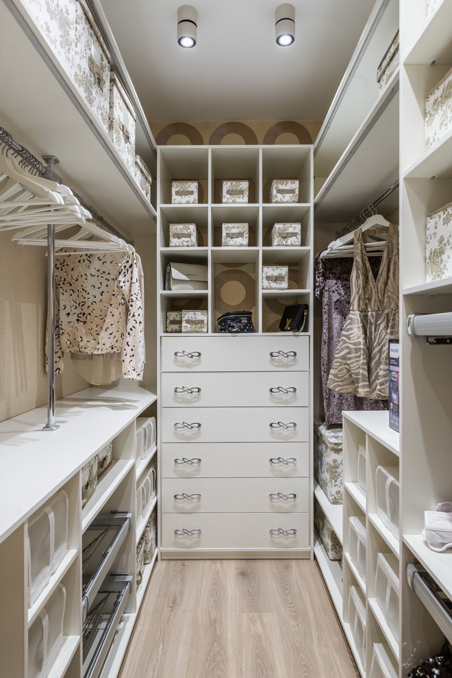 This is an example of a small contemporary women's walk-in wardrobe in Saint Petersburg with flat-panel cabinets, white cabinets, light hardwood floors and beige floor.
