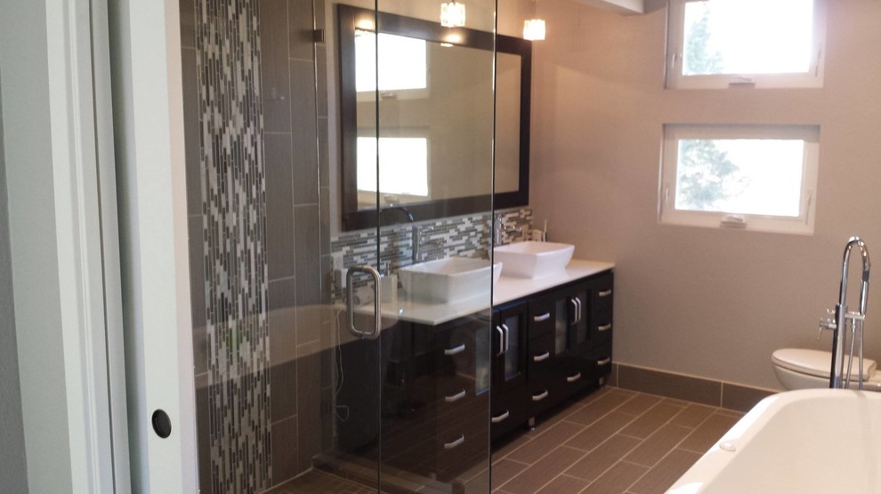 Photo of a mid-sized modern 3/4 bathroom in Other with black cabinets, a claw-foot tub, an open shower, a two-piece toilet, gray tile, porcelain tile, beige walls, porcelain floors, a vessel sink and engineered quartz benchtops.