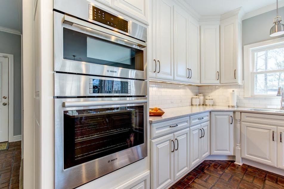 Eat-in kitchen - large traditional u-shaped brick floor eat-in kitchen idea in Birmingham with an undermount sink, raised-panel cabinets, white cabinets, quartz countertops, white backsplash, subway tile backsplash, stainless steel appliances and an island