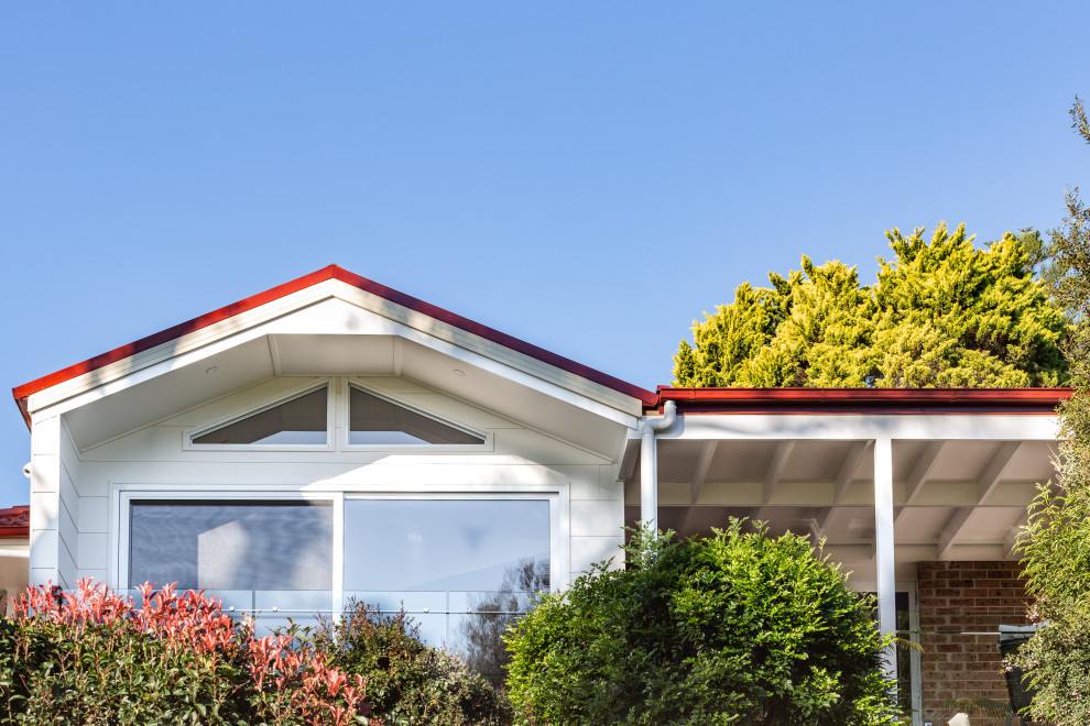 Mittelgroßes, Einstöckiges Modernes Reihenhaus mit weißer Fassadenfarbe, Satteldach, Ziegeldach, rotem Dach und Verschalung in Sydney