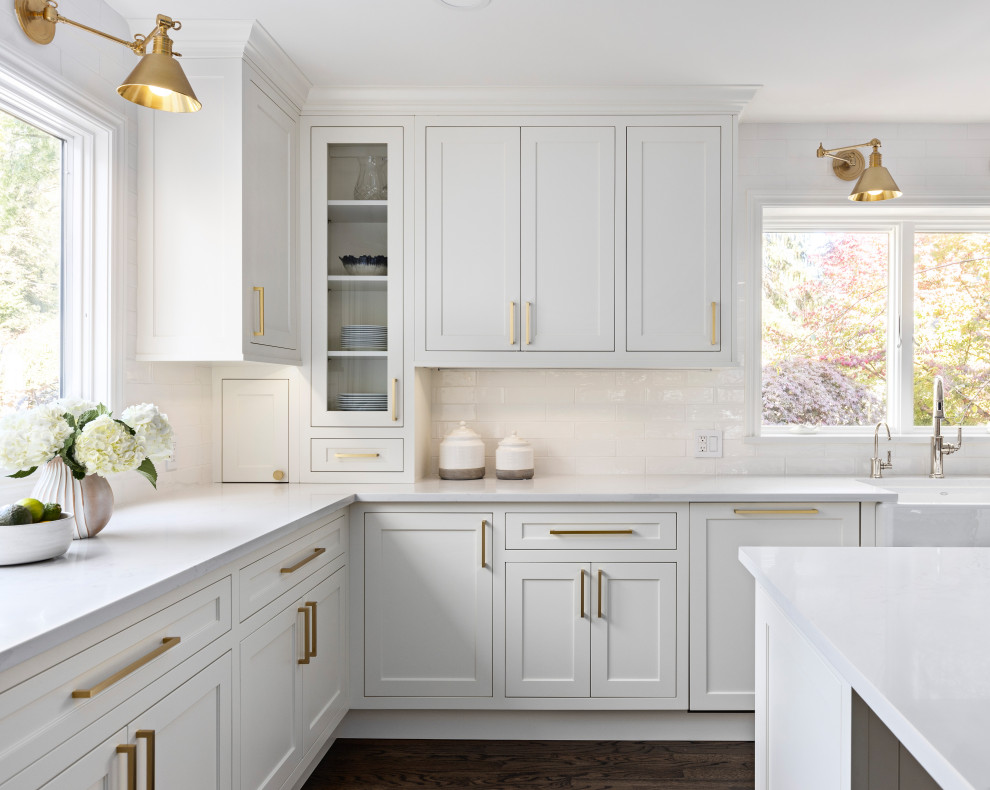 Design ideas for a medium sized traditional u-shaped enclosed kitchen in Detroit with beaded cabinets, white cabinets, engineered stone countertops, white splashback, metro tiled splashback, stainless steel appliances, dark hardwood flooring, an island, brown floors and white worktops.