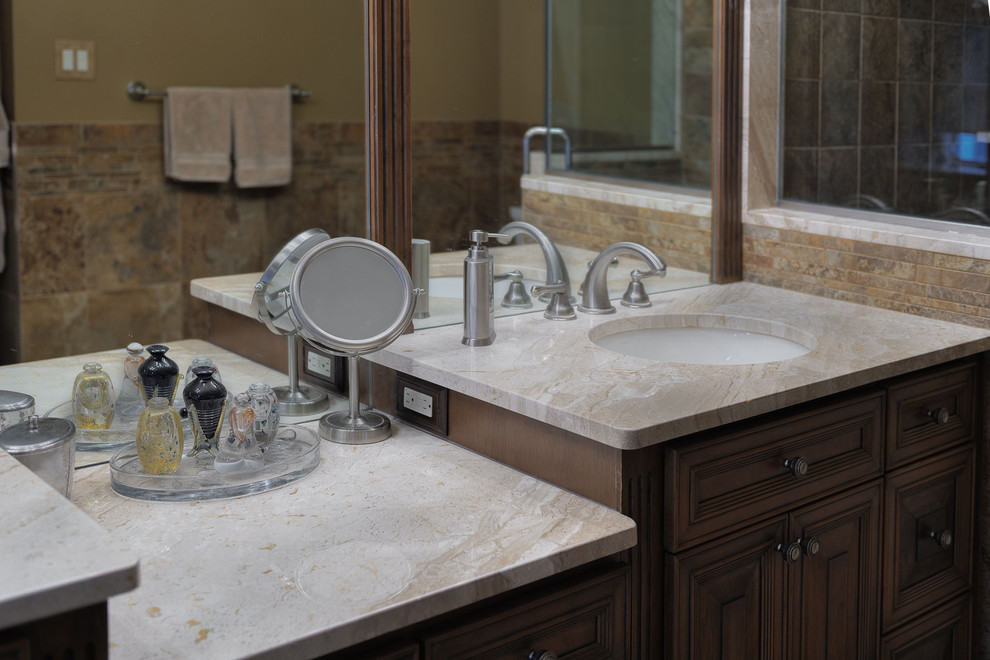 Photo of a large traditional master bathroom in Philadelphia with an undermount sink, raised-panel cabinets, dark wood cabinets, marble benchtops, a drop-in tub, a corner shower, a two-piece toilet, brown tile, porcelain tile, brown walls and porcelain floors.