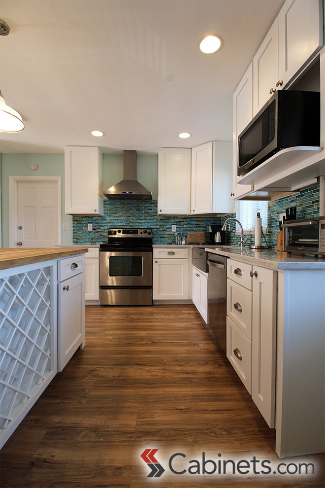 Mid-sized transitional l-shaped eat-in kitchen in Tampa with a farmhouse sink, shaker cabinets, white cabinets, blue splashback, stainless steel appliances and with island.