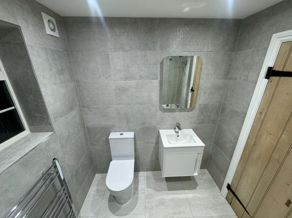 На фото: маленькая серо-белая ванная комната в современном стиле с фасадами в стиле шейкер, белыми фасадами, ванной в нише, душем в нише, унитазом-моноблоком, серой плиткой, цементной плиткой, серыми стенами, полом из керамической плитки, подвесной раковиной, столешницей из гранита, серым полом, душем с раздвижными дверями, белой столешницей, тумбой под одну раковину, подвесной тумбой и кессонным потолком для на участке и в саду с