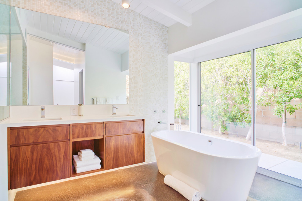 Design ideas for a contemporary bathroom in Los Angeles with flat-panel cabinets, medium wood cabinets, a freestanding tub, white tile, mosaic tile, white walls, concrete floors, an undermount sink, brown floor, white benchtops, a double vanity, a floating vanity, exposed beam, timber and vaulted.