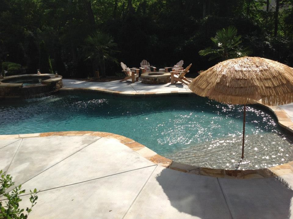 This is an example of a large traditional backyard custom-shaped pool in Charlotte with a hot tub and natural stone pavers.