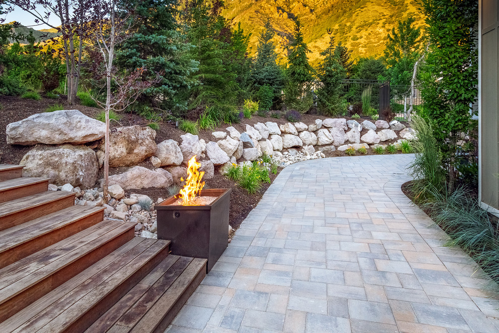 Transitional backyard garden in Salt Lake City with a retaining wall and river rock.