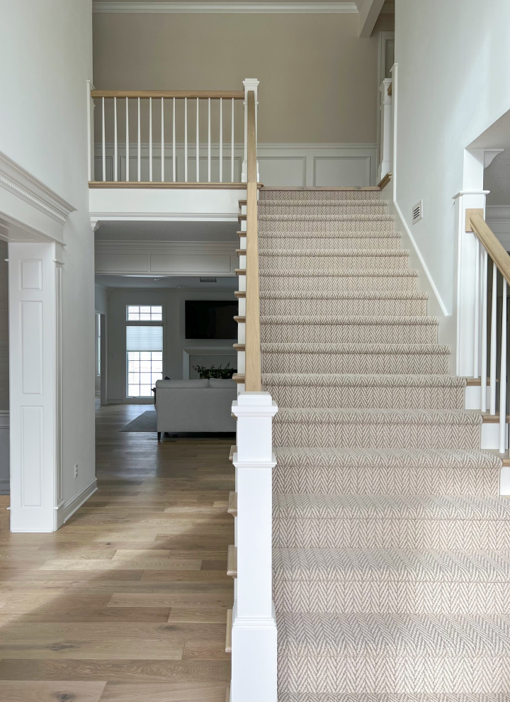 Стильный дизайн: большая прямая лестница в стиле неоклассика (современная классика) с ступенями с ковровым покрытием, ковровыми подступенками, деревянными перилами и панелями на части стены - последний тренд