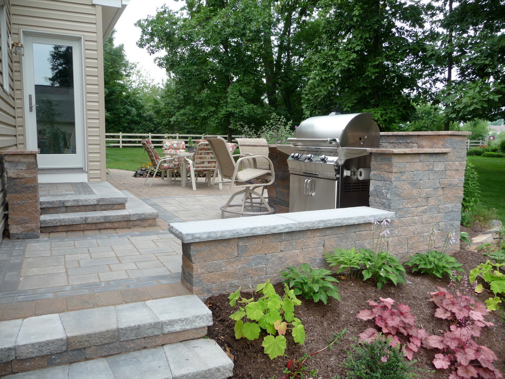This is an example of a mid-sized transitional backyard patio in Philadelphia with natural stone pavers and no cover.