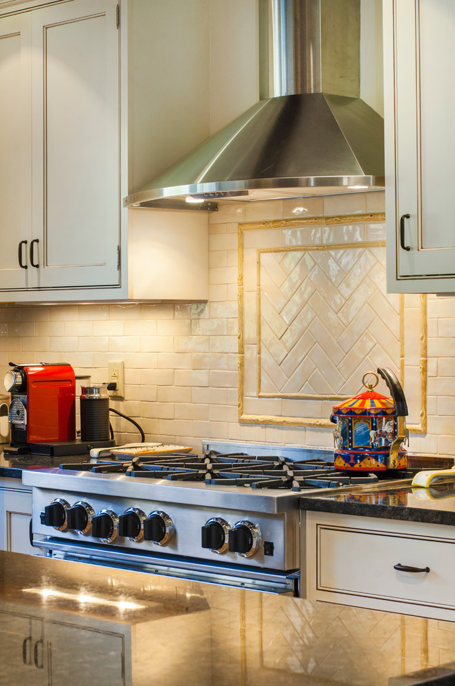 Example of a transitional u-shaped medium tone wood floor kitchen design in New York with a farmhouse sink, beaded inset cabinets, white cabinets, granite countertops, beige backsplash, subway tile backsplash, stainless steel appliances and an island