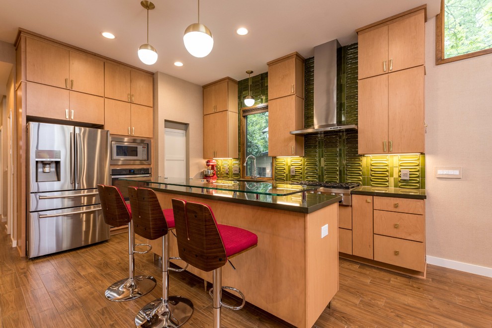 Photo of a mid-sized midcentury l-shaped open plan kitchen in Austin with a farmhouse sink, flat-panel cabinets, light wood cabinets, quartz benchtops, green splashback, porcelain splashback, stainless steel appliances, ceramic floors, with island and brown floor.