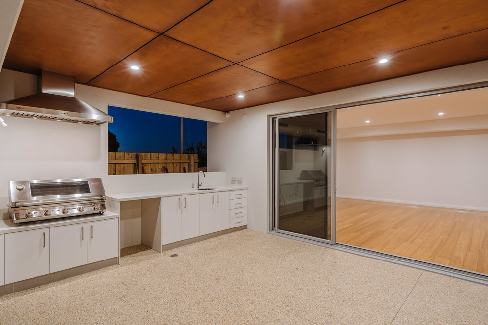 This is an example of a large contemporary backyard deck in Perth with an outdoor kitchen and a roof extension.