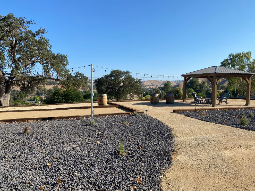 This is an example of a medium sized classic back patio in San Luis Obispo with a fire feature, concrete paving and a pergola.