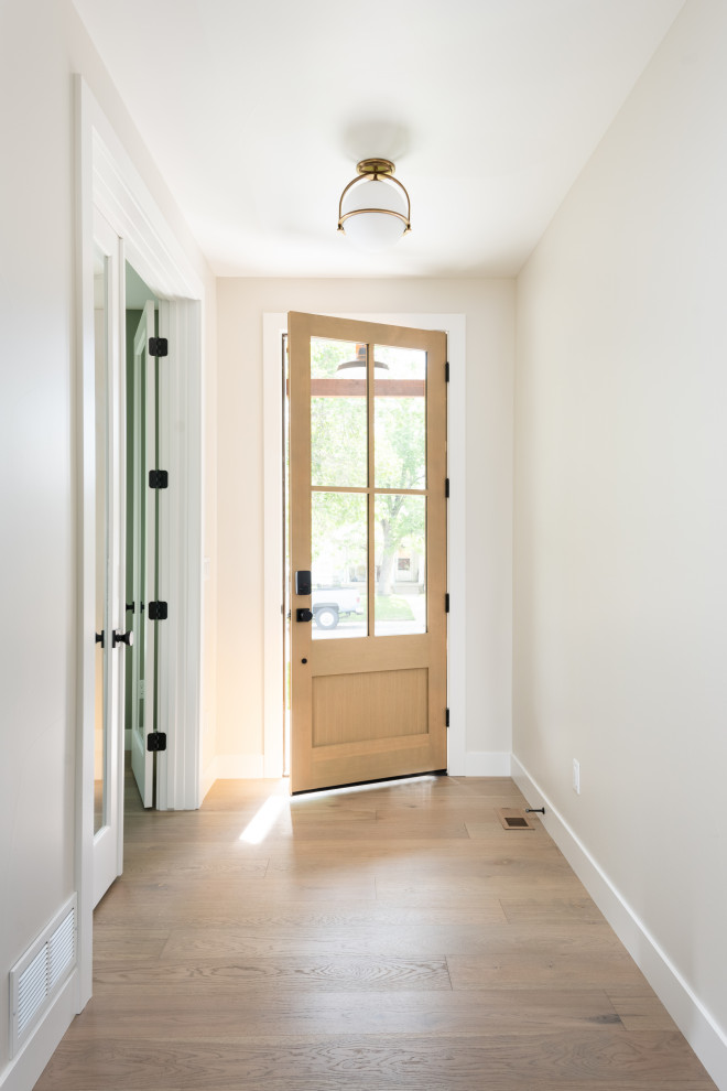 Пример оригинального дизайна: входная дверь среднего размера в стиле неоклассика (современная классика) с белыми стенами, паркетным полом среднего тона, одностворчатой входной дверью и входной дверью из светлого дерева