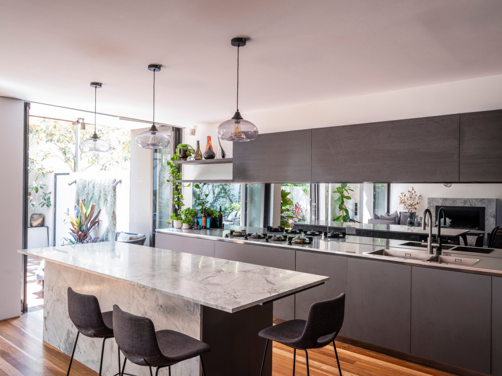 Design ideas for a large contemporary kitchen in Sydney with stainless steel benchtops, mirror splashback, a double-bowl sink, flat-panel cabinets, medium hardwood floors and with island.