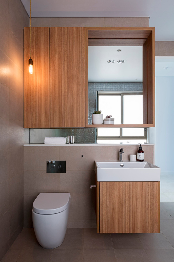 This is an example of a mid-sized contemporary bathroom in Sydney with a freestanding tub, flat-panel cabinets, medium wood cabinets, a one-piece toilet and brown tile.