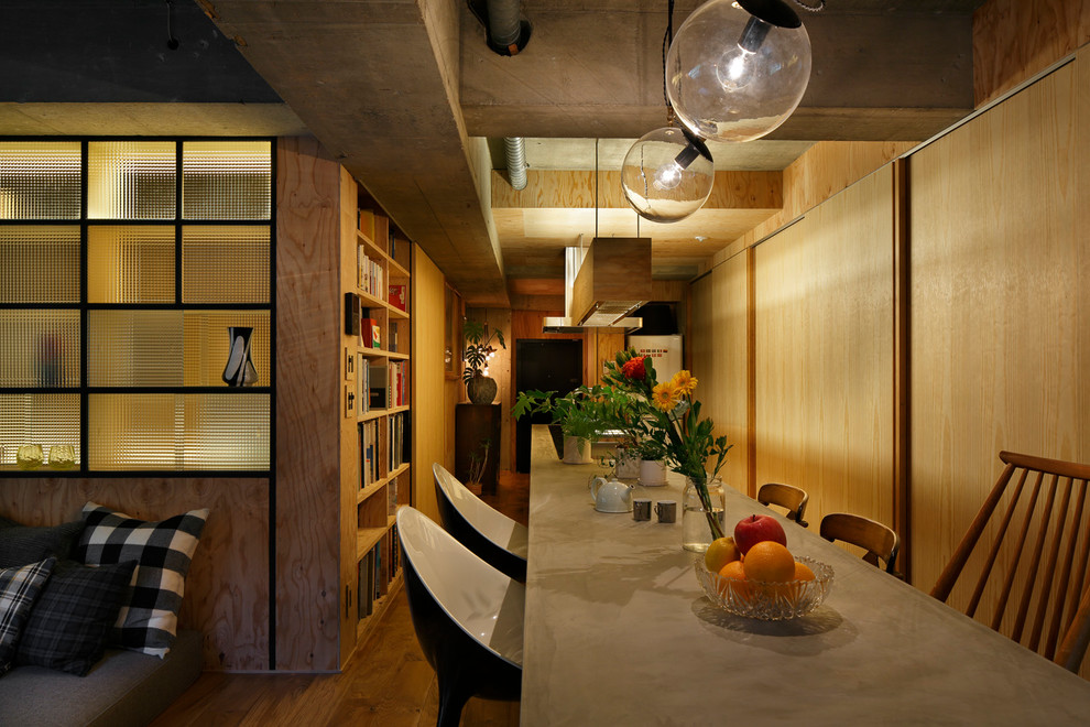 Midcentury open plan dining in Tokyo with brown walls, medium hardwood floors and brown floor.
