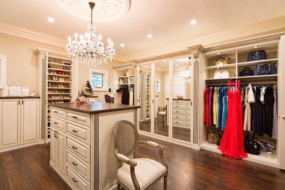 This is an example of a large traditional women's dressing room in Los Angeles with raised-panel cabinets, dark hardwood floors and beige cabinets.