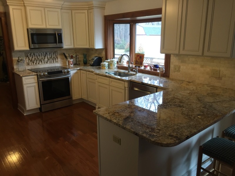 Eat-in kitchen - mid-sized transitional u-shaped medium tone wood floor eat-in kitchen idea with an undermount sink, flat-panel cabinets, white cabinets, granite countertops, beige backsplash, stone tile backsplash, stainless steel appliances and a peninsula