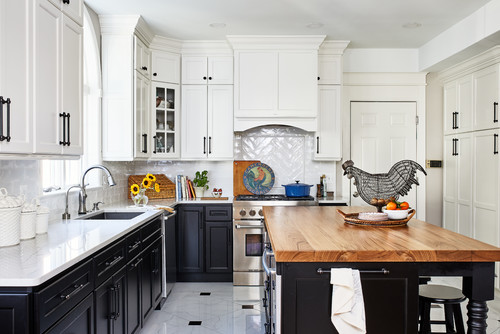 Bright transitional kitchen with two-tone RTA cabinets—white shaker uppers and black base units—quartz counters, herringbone tile backsplash, and a warm wood-top island.