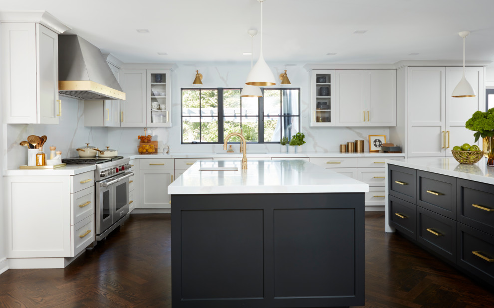 This is an example of an expansive transitional u-shaped eat-in kitchen in New York with an undermount sink, shaker cabinets, white cabinets, quartz benchtops, white splashback, engineered quartz splashback, stainless steel appliances, painted wood floors, multiple islands, brown floor and grey benchtop.