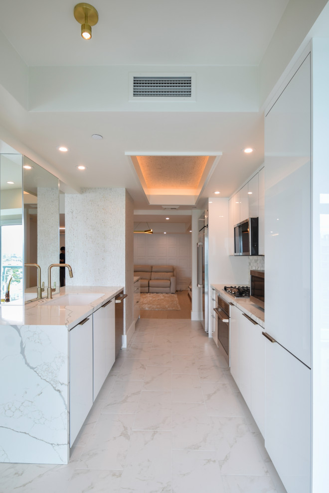 Design ideas for a mid-sized contemporary galley kitchen in Los Angeles with an undermount sink, flat-panel cabinets, white cabinets, quartz benchtops, white splashback, marble splashback, stainless steel appliances, porcelain floors, white floor, white benchtop and wallpaper.