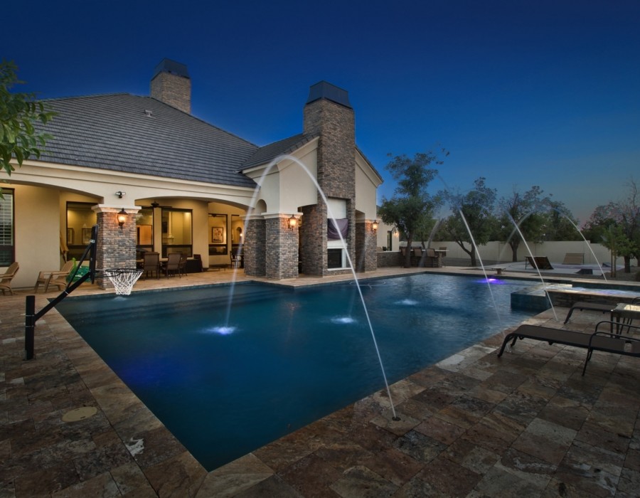 Photo of a large traditional backyard rectangular lap pool in Phoenix with a hot tub and natural stone pavers.