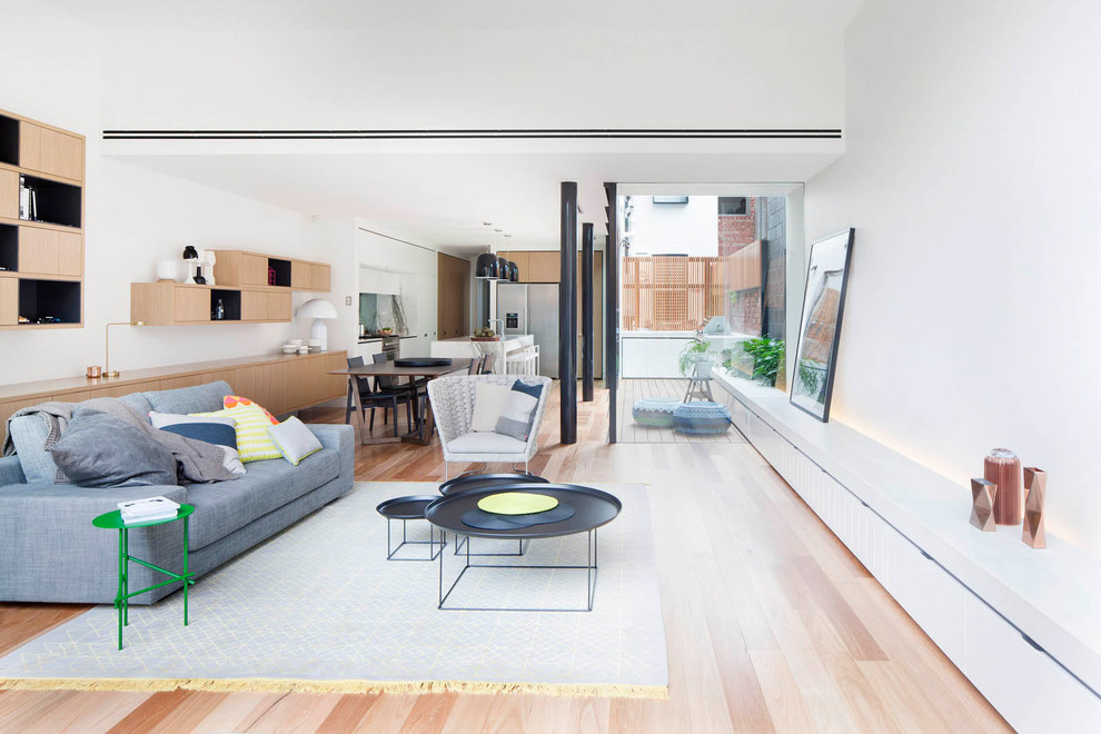 Photo of a contemporary open concept living room in Melbourne with white walls, light hardwood floors and beige floor.