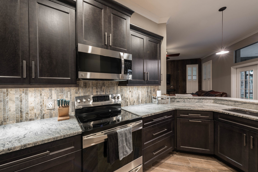 Large transitional l-shaped porcelain tile and brown floor eat-in kitchen photo in Orlando with shaker cabinets, gray cabinets, granite countertops, multicolored backsplash, travertine backsplash, stainless steel appliances, a peninsula and multicolored countertops