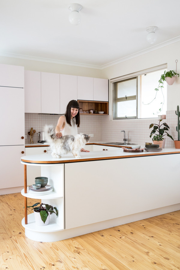 Small midcentury u-shaped open plan kitchen in Adelaide with flat-panel cabinets, laminate benchtops, white splashback, ceramic splashback, white appliances and light hardwood floors.