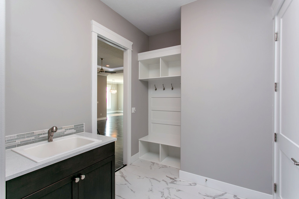 Photo of a mid-sized modern l-shaped dedicated laundry room in Seattle with a drop-in sink, shaker cabinets, dark wood cabinets, quartz benchtops, grey walls, marble floors, a side-by-side washer and dryer, white floor and white benchtop.