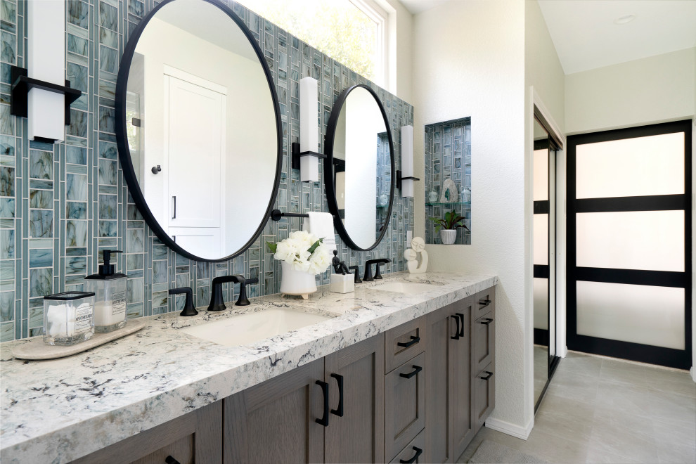 Photo of a mid-sized transitional master bathroom in San Diego with shaker cabinets, brown cabinets, a two-piece toilet, gray tile, porcelain tile, white walls, pebble tile floors, an undermount sink, engineered quartz benchtops, white floor, a hinged shower door, blue benchtops, a shower seat, a double vanity and a built-in vanity.