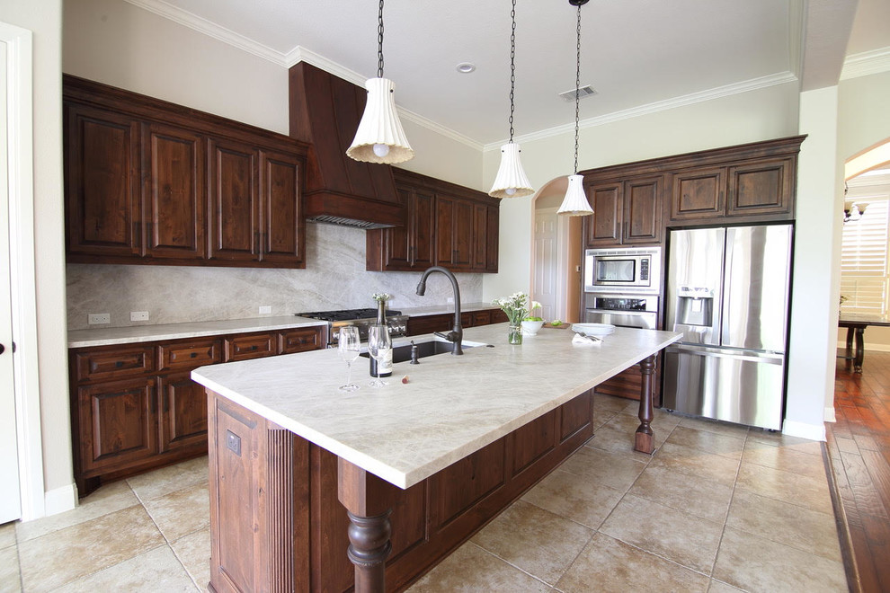 Large transitional l-shaped ceramic tile and beige floor enclosed kitchen photo with an undermount sink, dark wood cabinets, beige backsplash, stainless steel appliances and an island