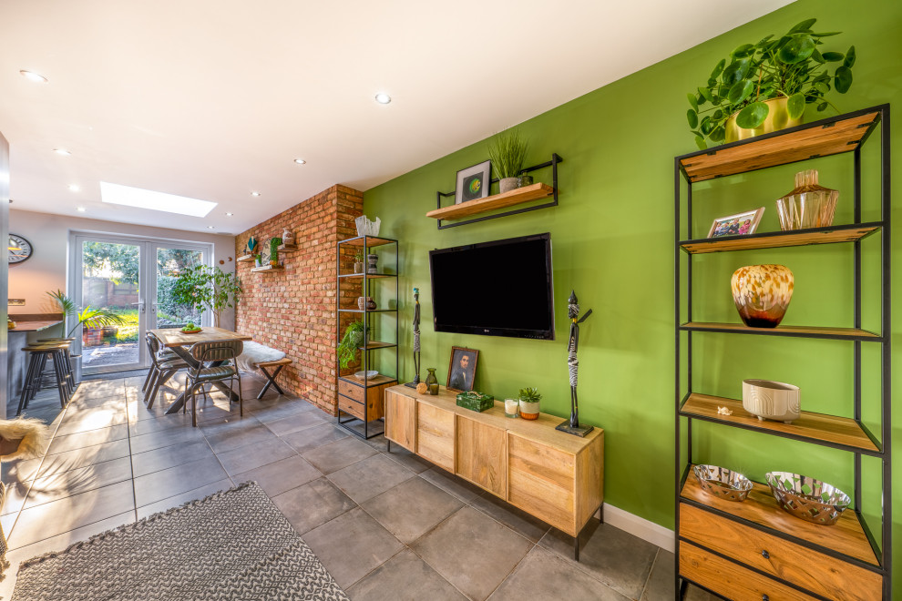 This is an example of a mid-sized industrial living room in London with green walls, porcelain floors, no fireplace, a wall-mounted tv and grey floor.