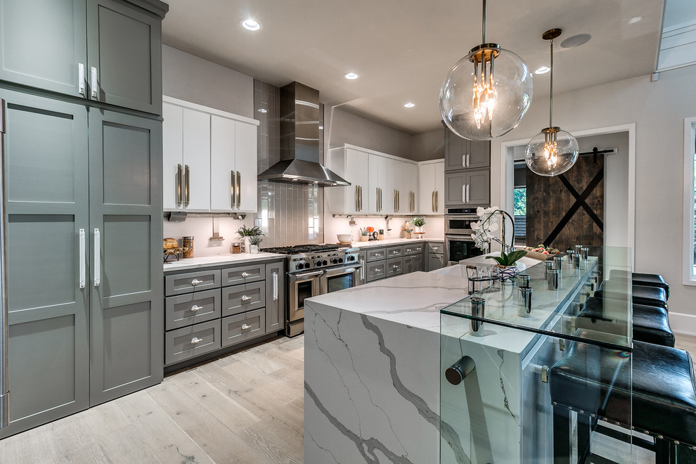 Kitchen - transitional light wood floor kitchen idea in Oklahoma City with shaker cabinets, gray cabinets, gray backsplash, stainless steel appliances and an island