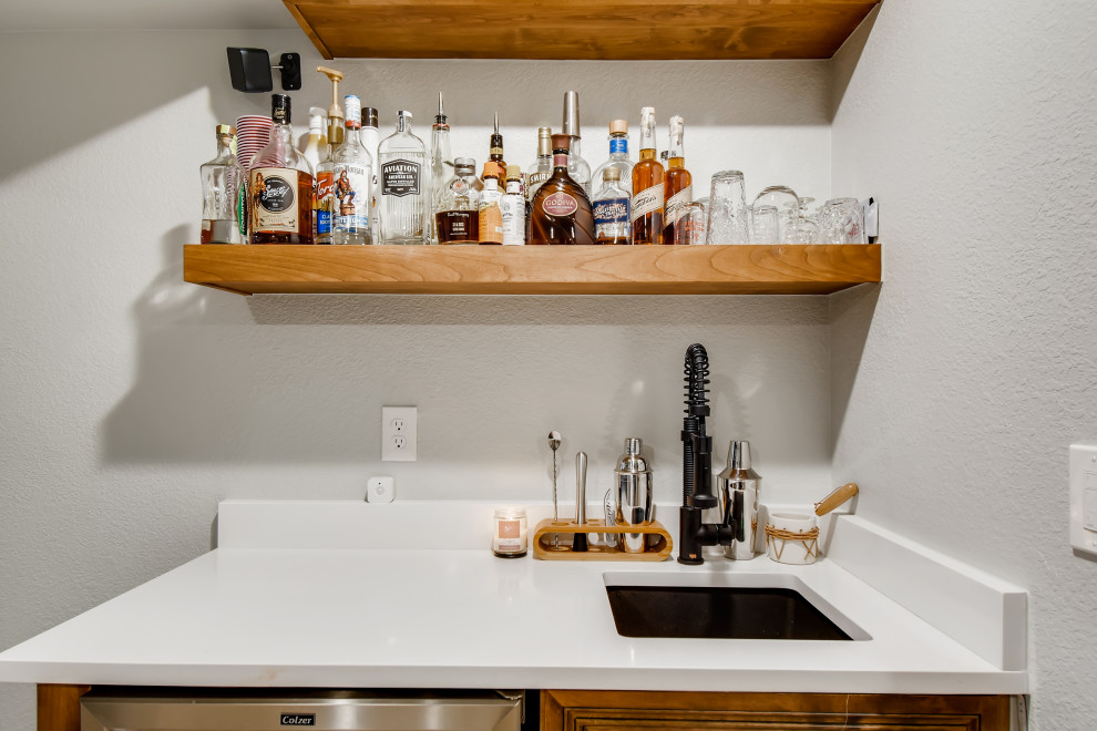 Inspiration for a small modern single-wall wet bar in Denver with an undermount sink, brown cabinets, quartzite benchtops, vinyl floors, grey floor and white benchtop.